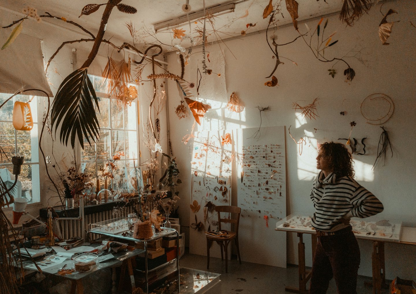 Künstlerin steht in ihrem Atelier, umgeben von botanischen Installationen.
